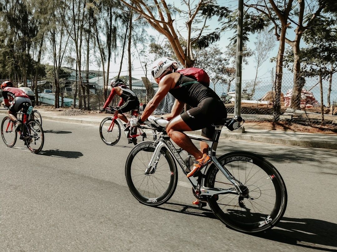 Tre triathleter cyklar på tempocyklar längs en kustväg
